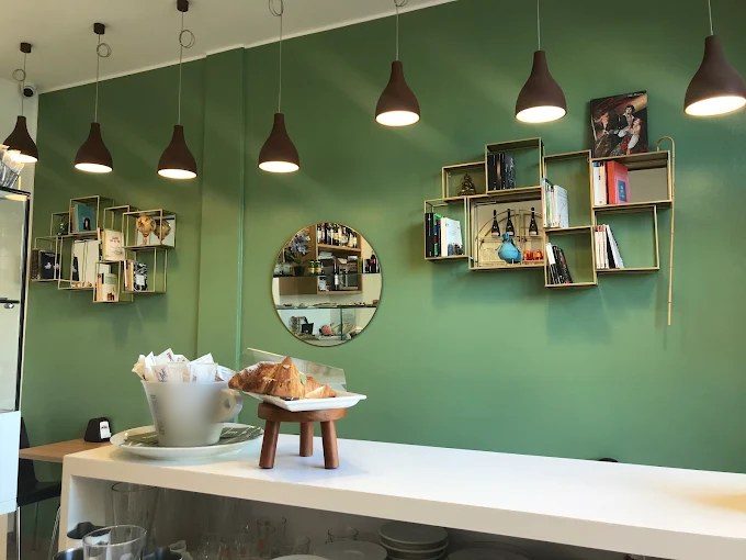 Bar con parete verde, sospensioni a campana e mensole luminose