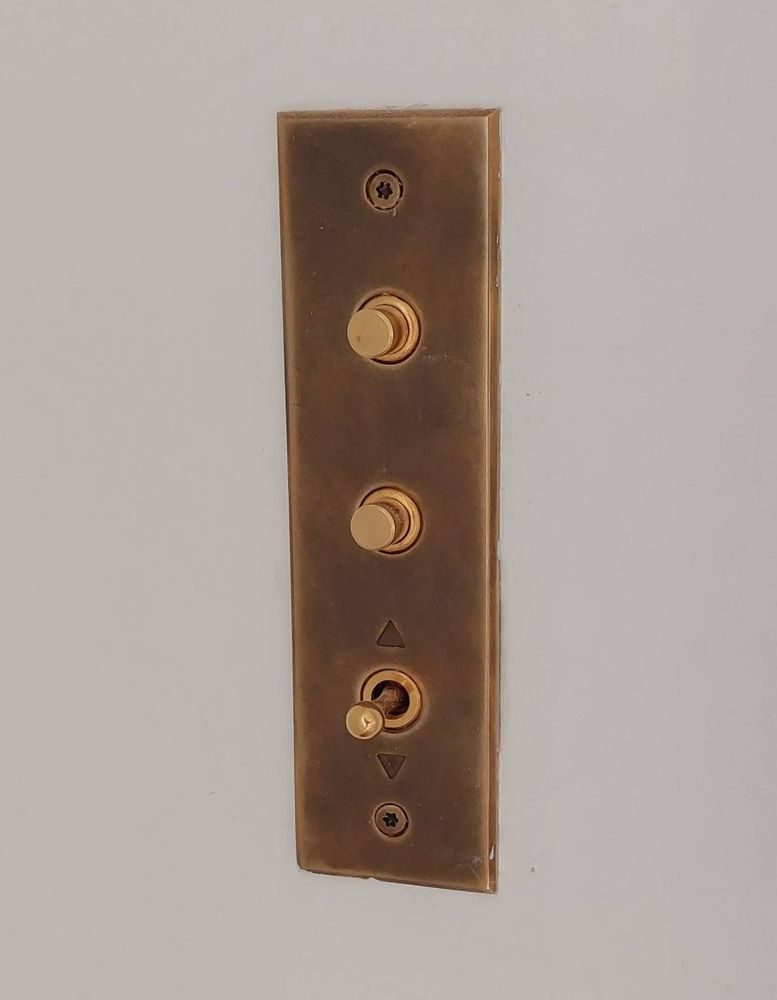 Placca in ottone brunito con due pulsanti e una leva